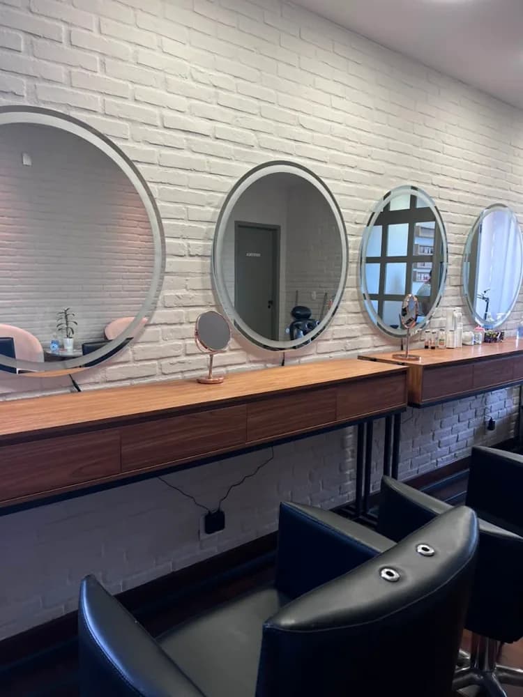 Estações de trabalho da Kasa Beauty, com espelhos ovais sobre parede de tijolo branco