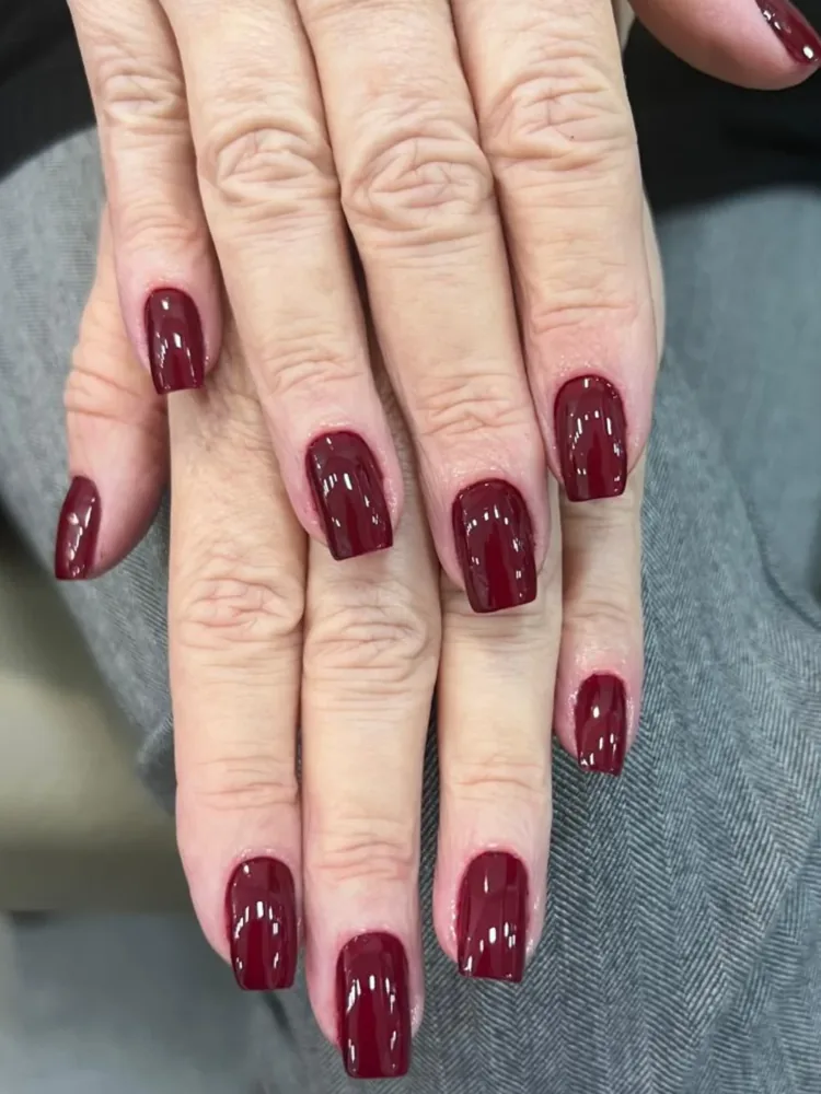 Mãos de cliente com esmaltação vermelho vinho e acabamento revisado, feita na Kasa Beauty
